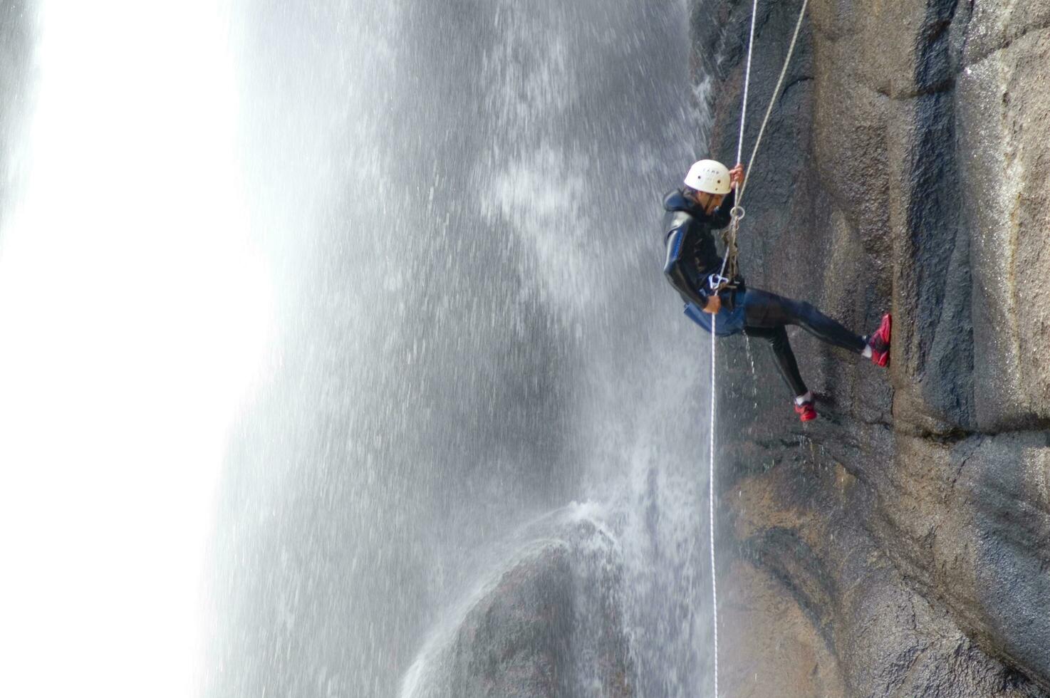 a person on a rope climbing up a waterfall photo