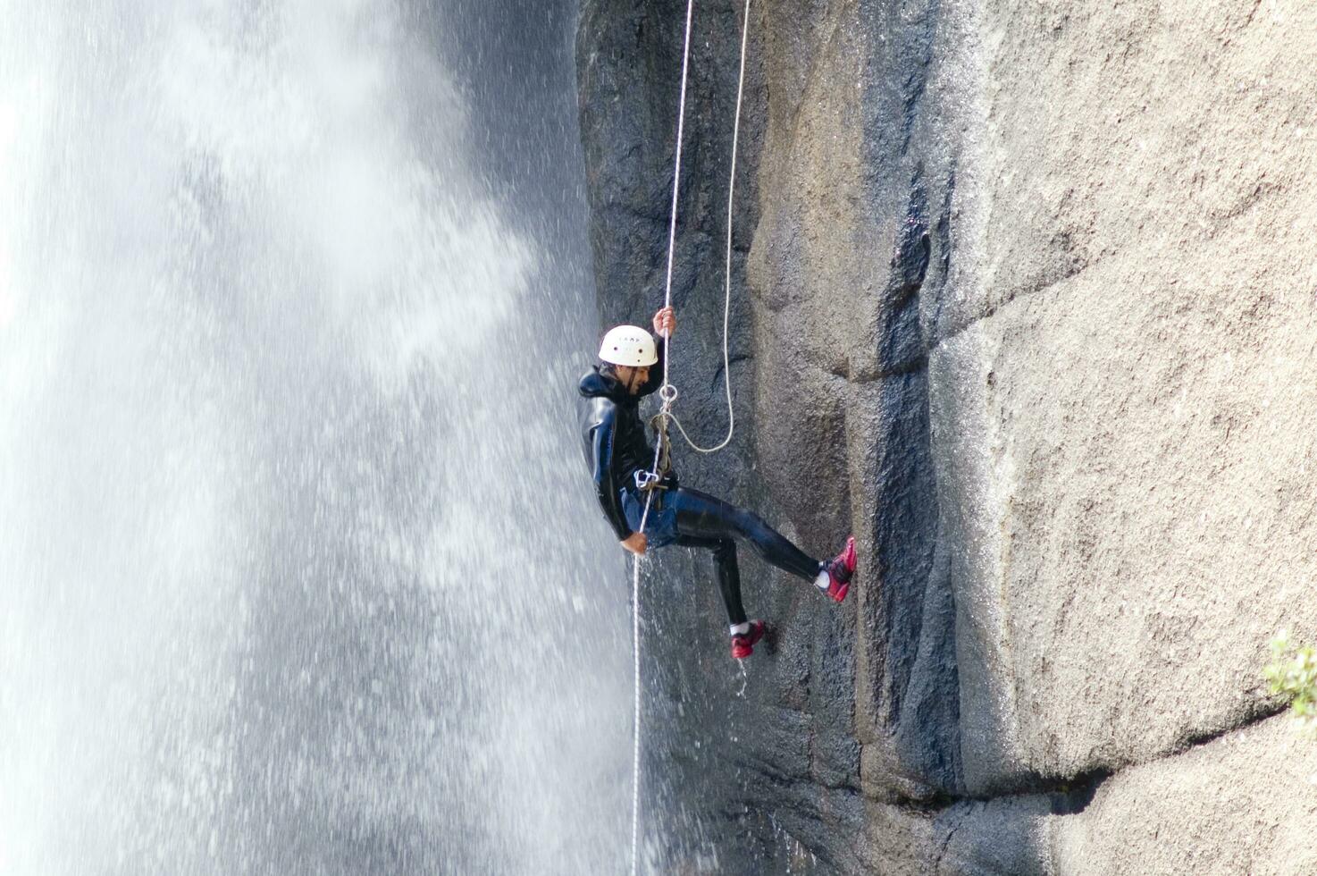 a person on a rope climbing up a waterfall photo