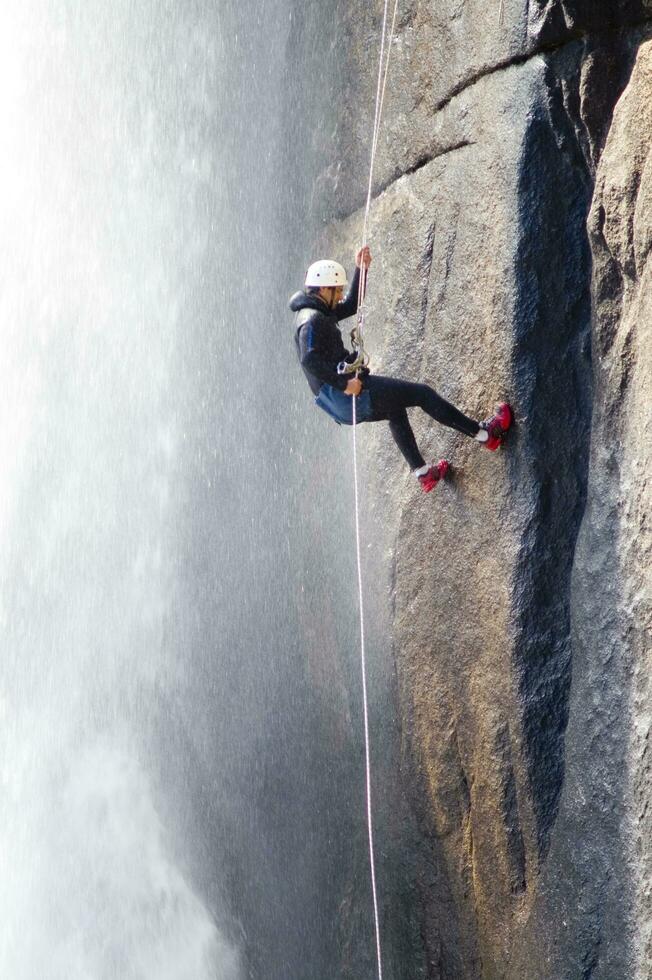 un persona en un cuerda alpinismo arriba un cascada foto