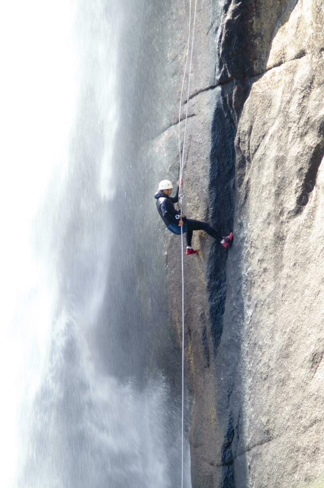 a person on a rope climbing up a waterfall photo