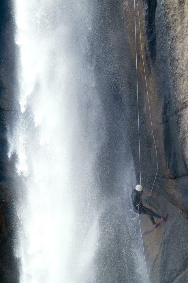 a person on a rope climbing up a waterfall photo