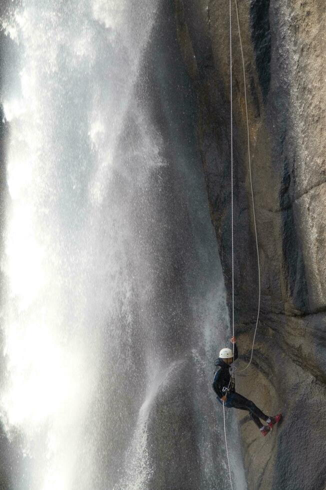 a person on a rope climbing up a waterfall photo