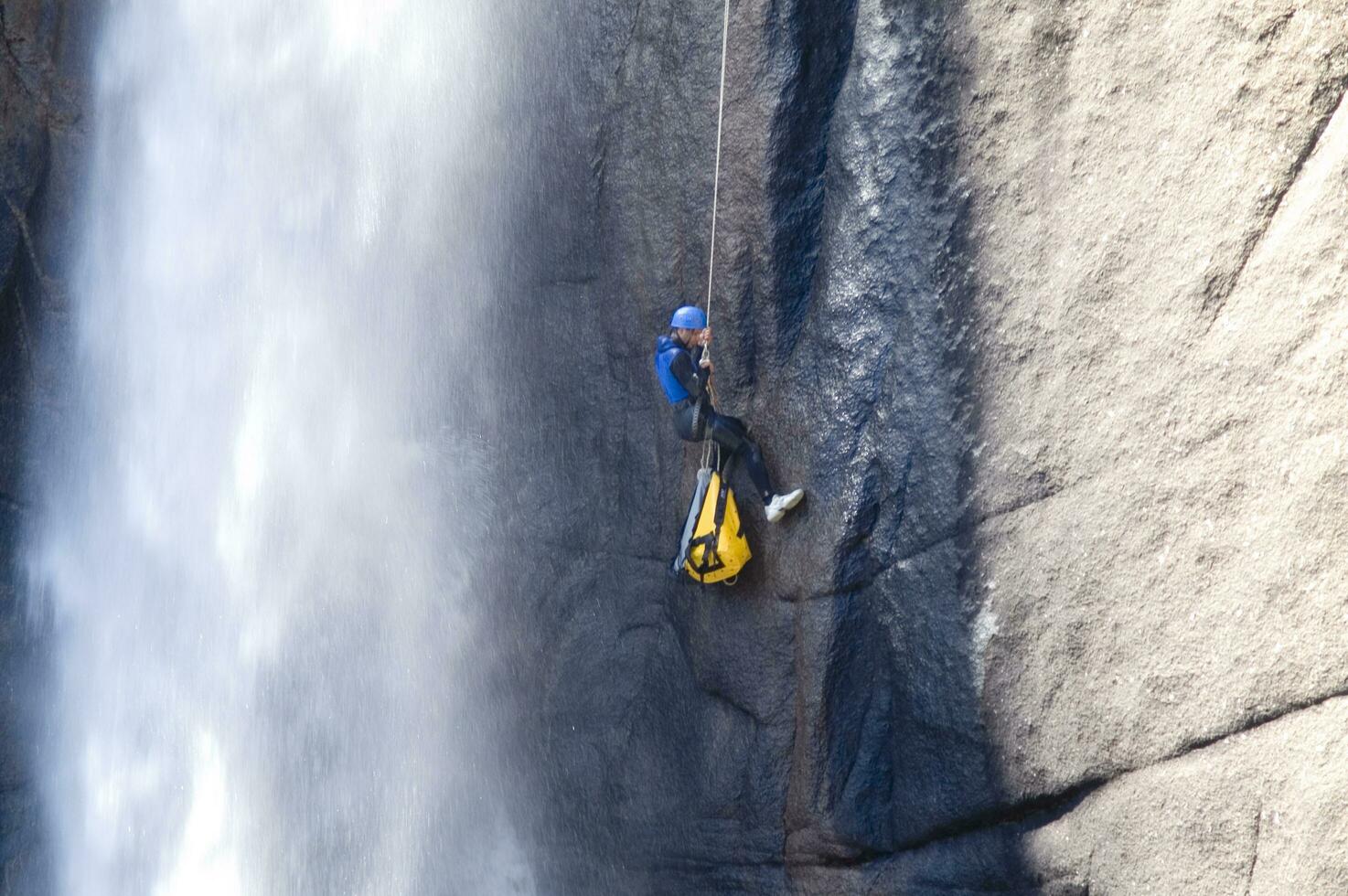 a person on a rope climbing up a waterfall photo