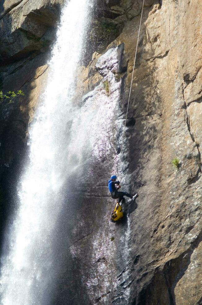 a person on a rope climbing up a waterfall photo