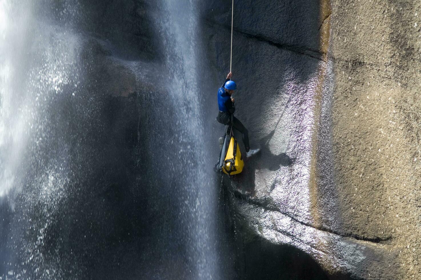 a person on a rope climbing up a waterfall photo