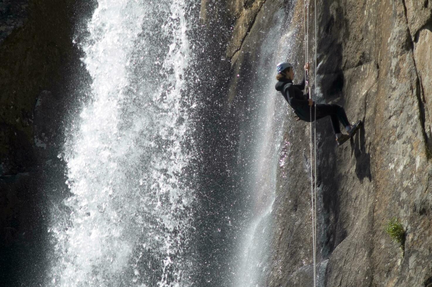 a person on a rope climbing up a waterfall photo