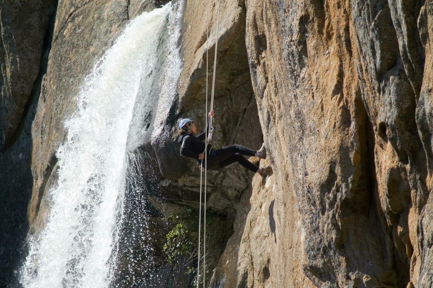 a person on a rope climbing up a waterfall photo