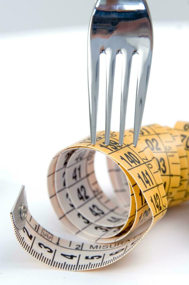 a fork and knife surrounded by measuring tape photo