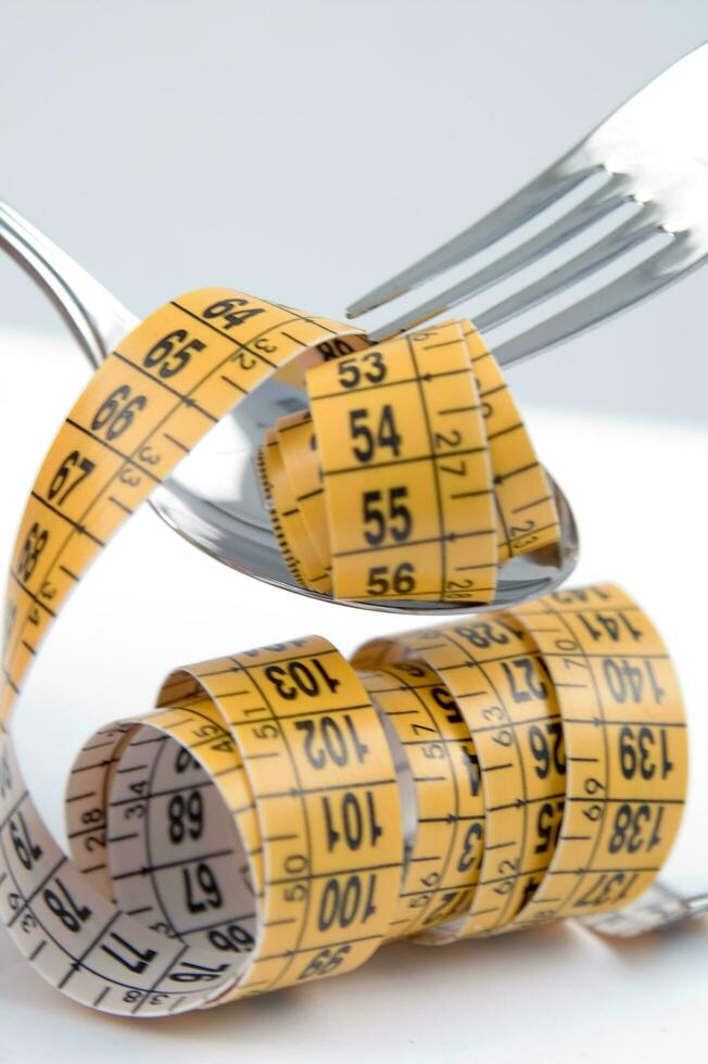 a fork and knife surrounded by measuring tape photo