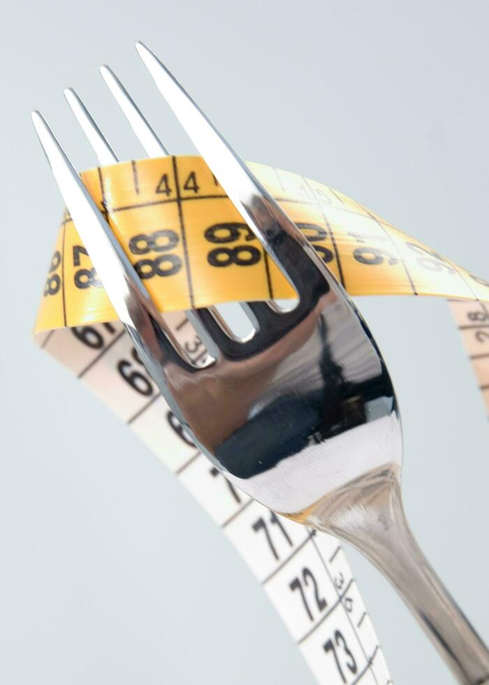 a fork and knife surrounded by measuring tape photo