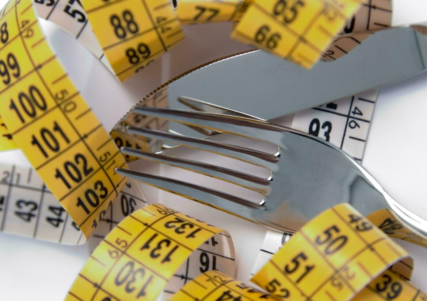 a fork and knife surrounded by measuring tape photo