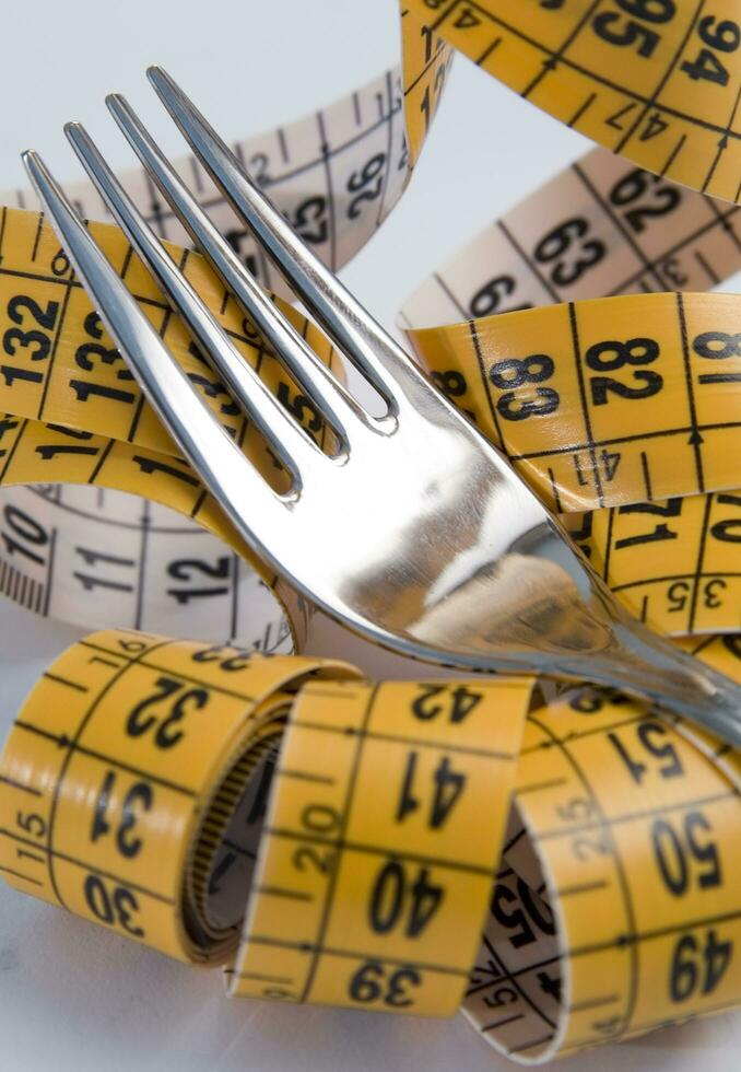 a fork and knife surrounded by measuring tape photo