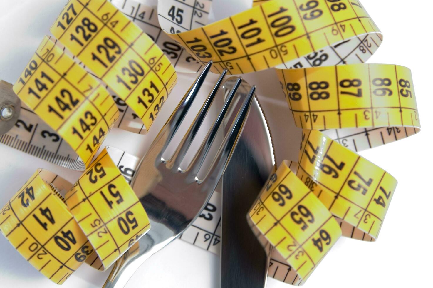 a fork and knife surrounded by measuring tape photo