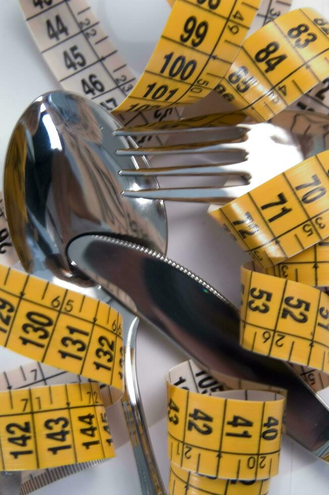 a fork and knife surrounded by measuring tape photo