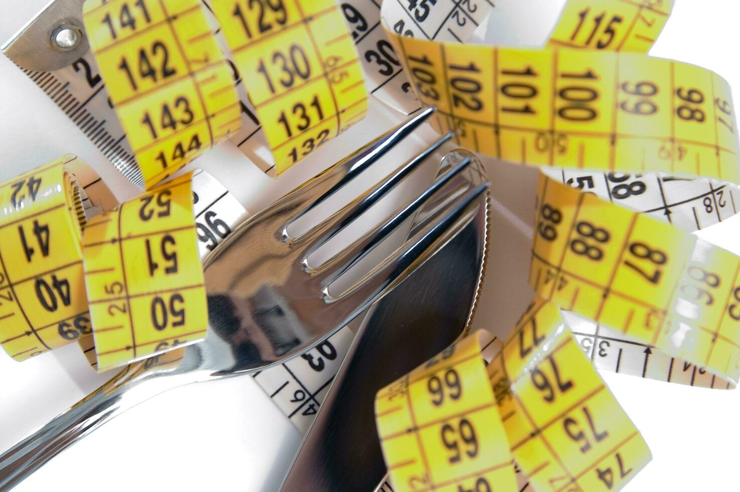 a fork and knife surrounded by measuring tape photo