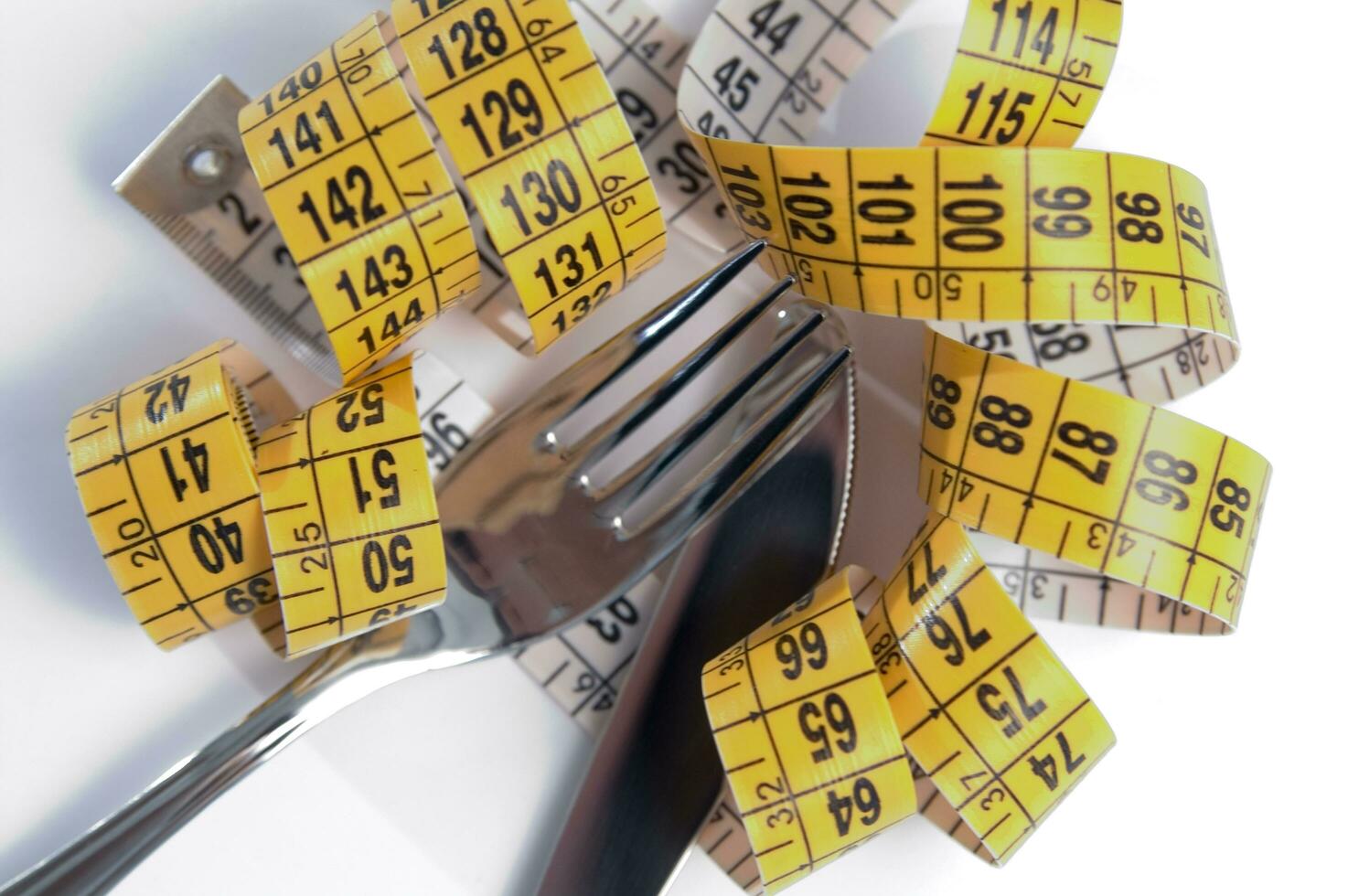 a fork and knife surrounded by measuring tape photo