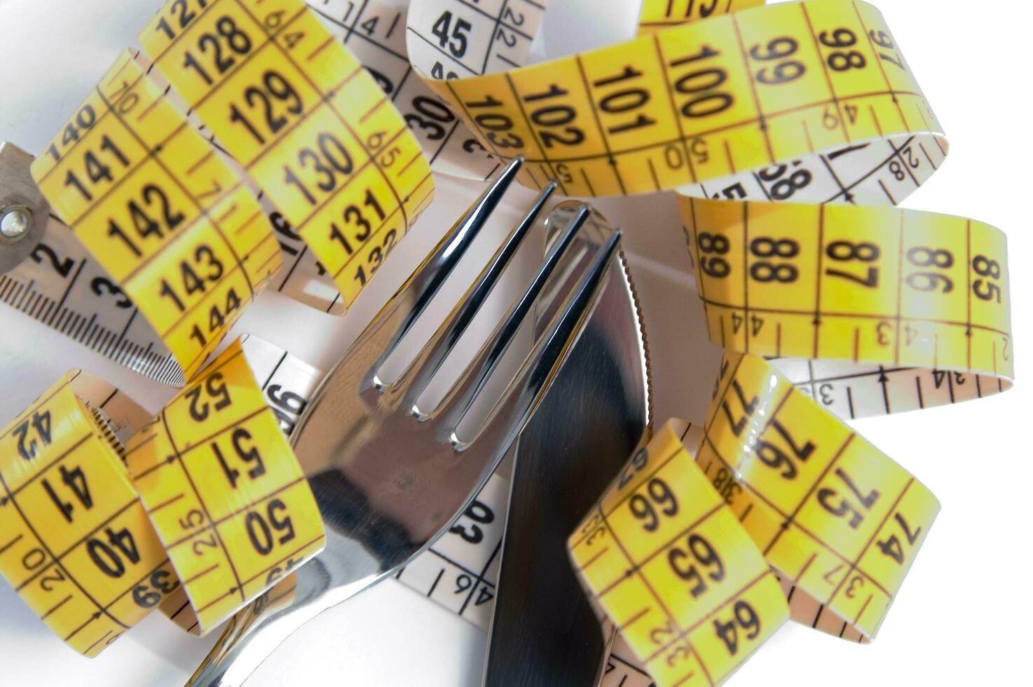 a fork and knife surrounded by measuring tape photo