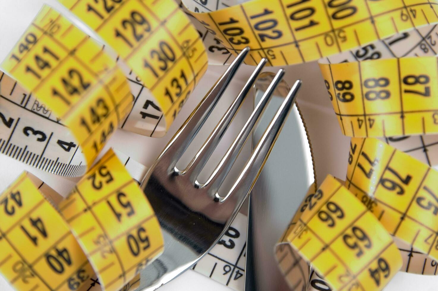 a fork and knife surrounded by measuring tape photo