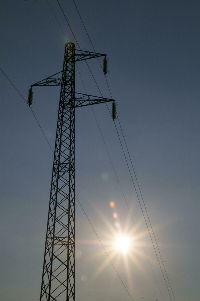 a silhouette of an electricity tower with the sun behind it photo