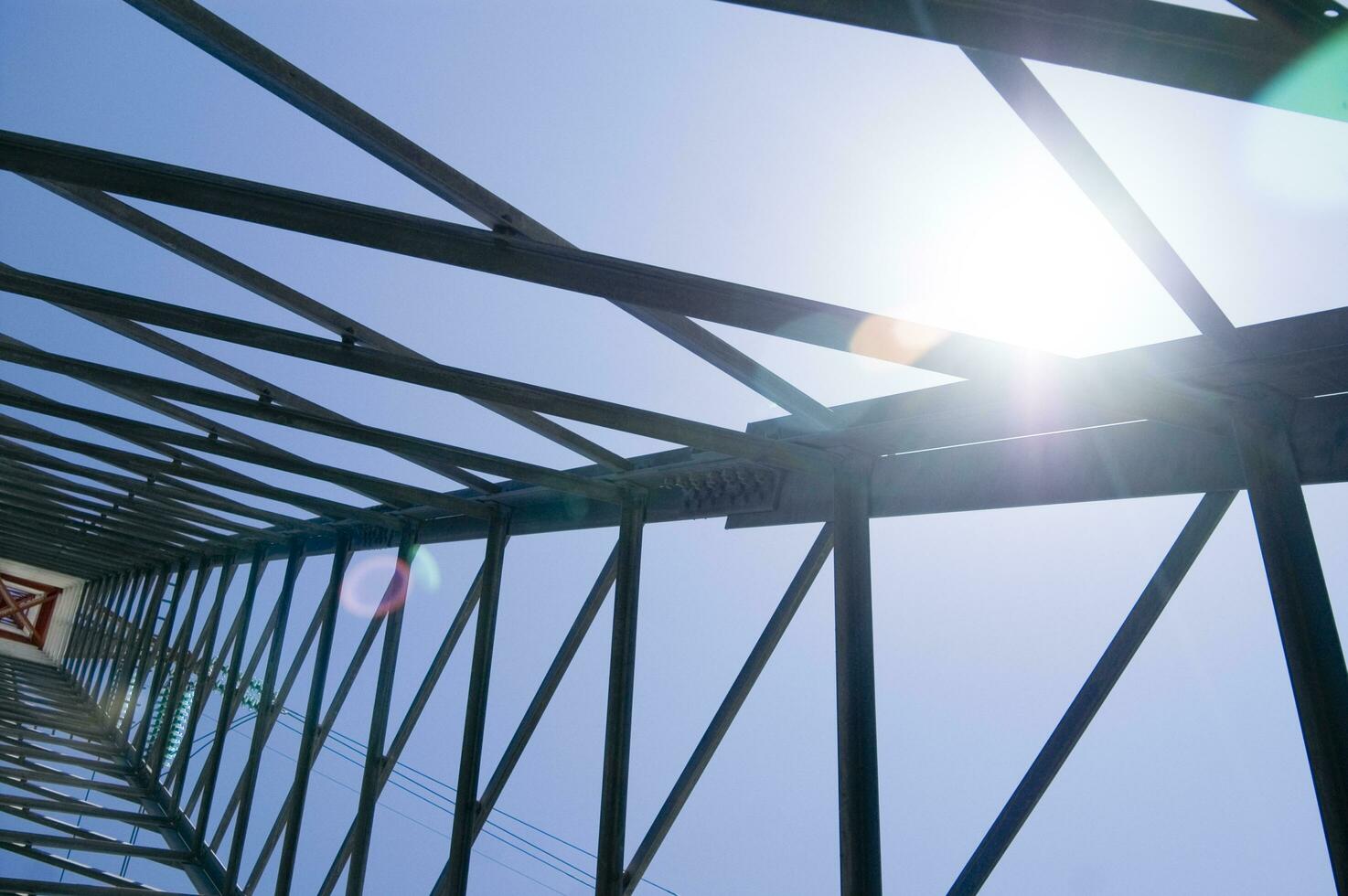 the sun shines through the metal structure of an oil rig photo
