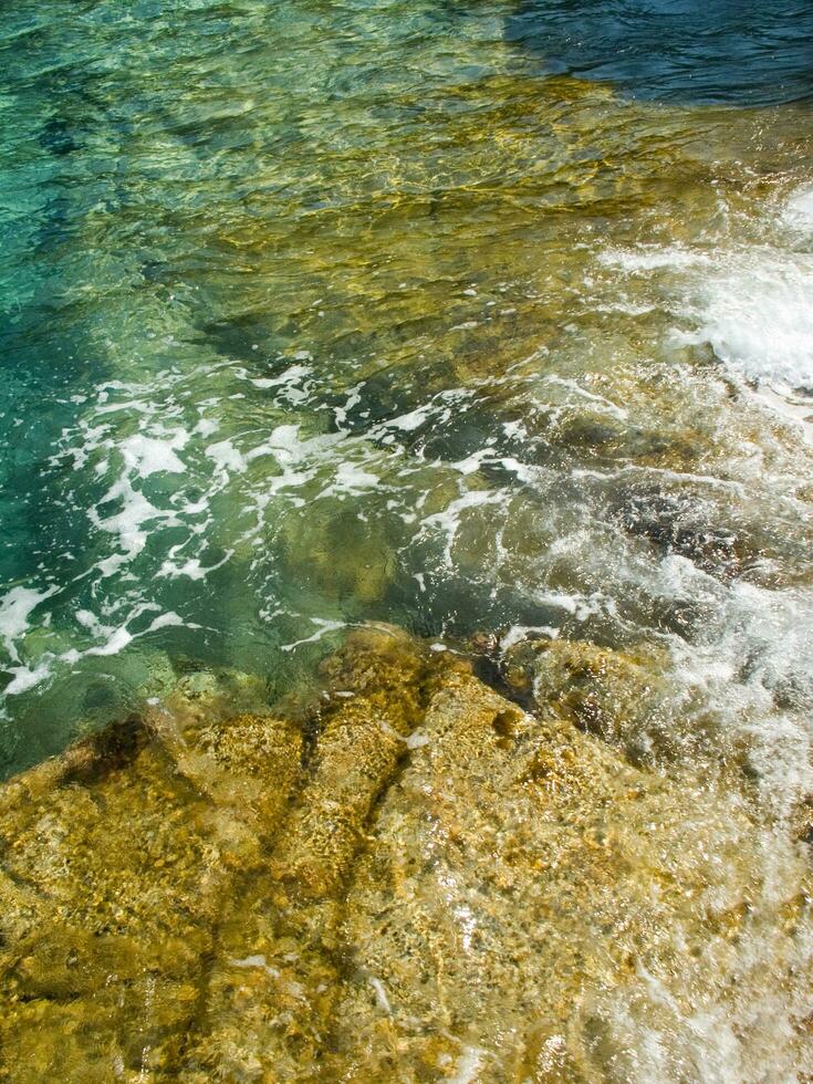 un rocoso apuntalar con olas estrellarse en contra el rocas foto