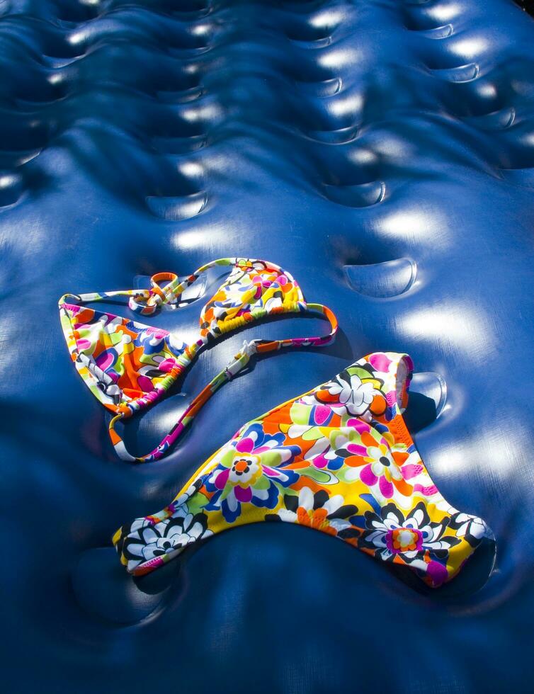 a pair of colorful swimsuits laying on a blue surface photo