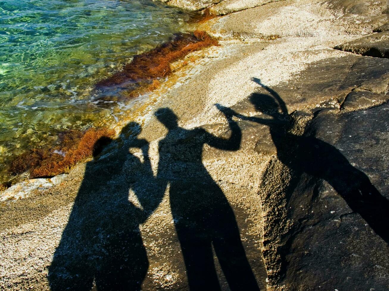 shadow of two people on rocks near water photo