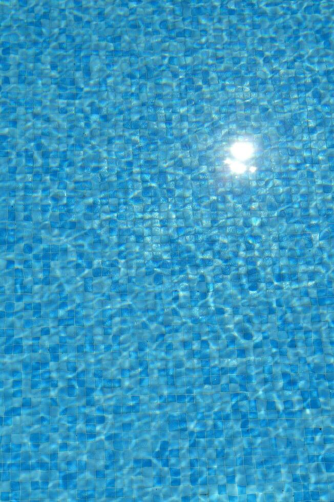 a blue pool with a sun shining on it photo