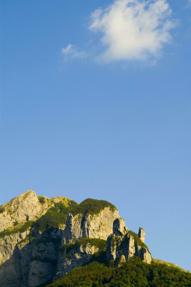 un montaña rango con un pocos casas en parte superior foto