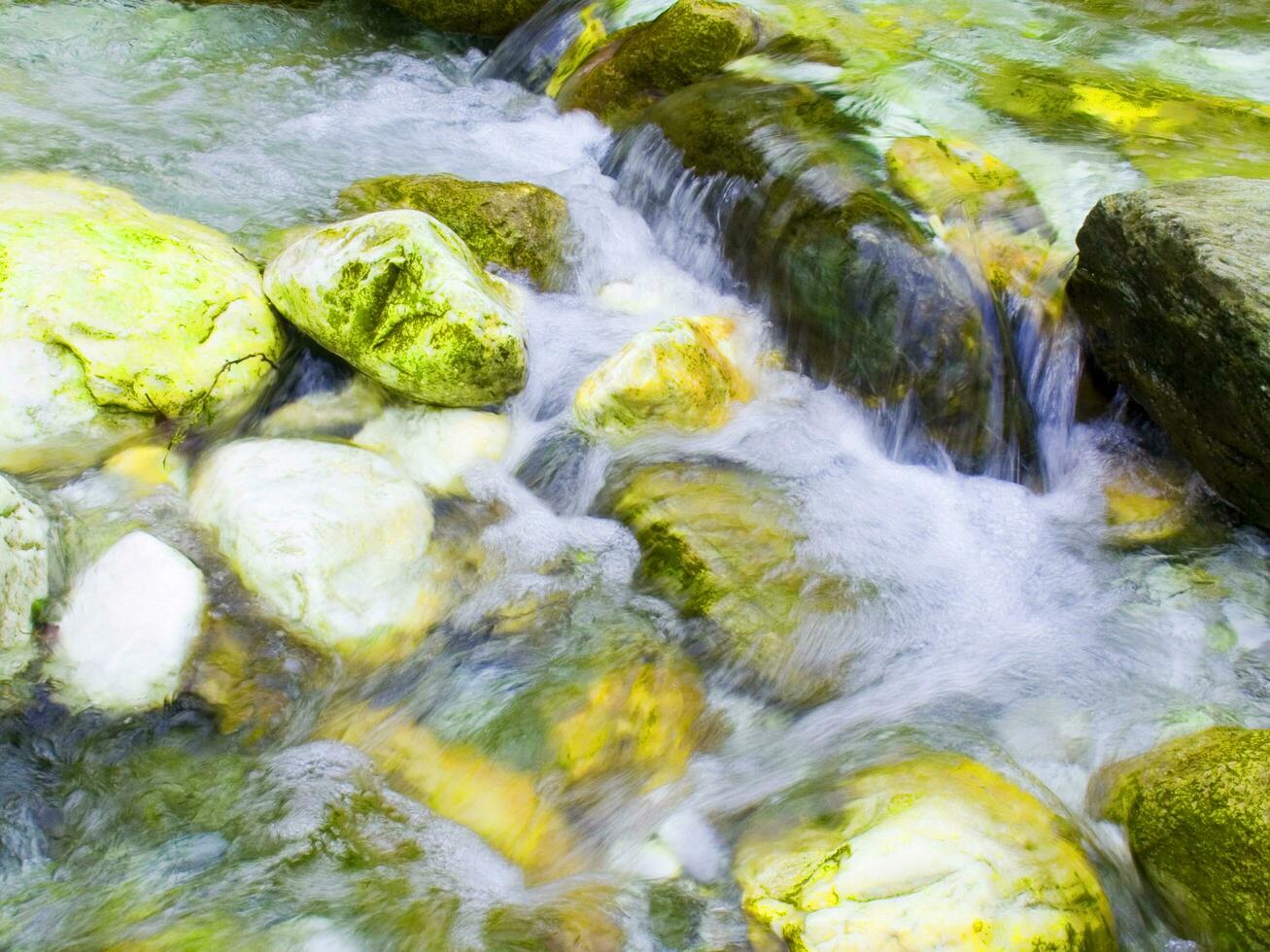 un hoja en un rock en un corriente foto