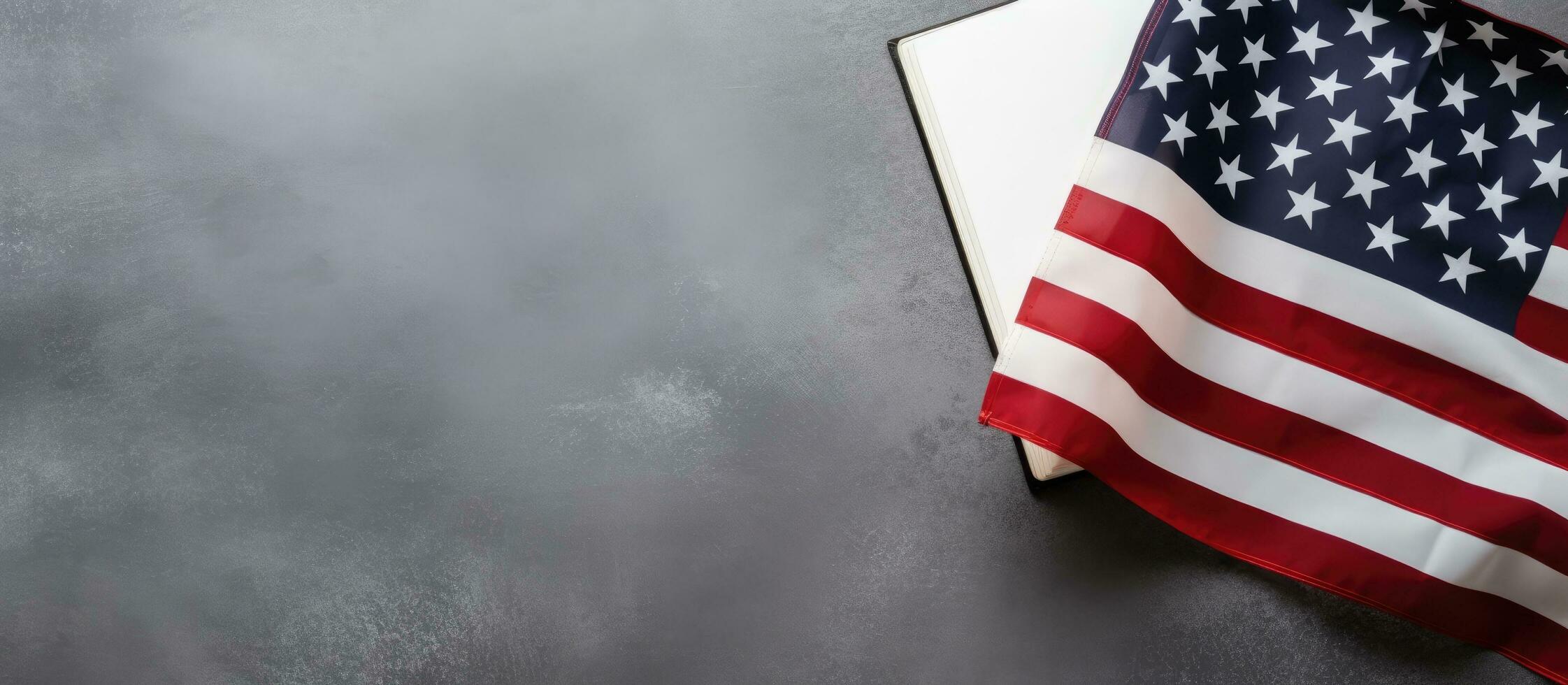 The flag of the United States of America and an empty notepad are seen from above on a gray concrete photo