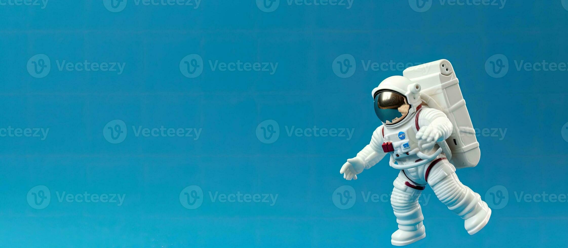 A close-up photo of a plastic toy astronaut figure on a blue background with copy space. is