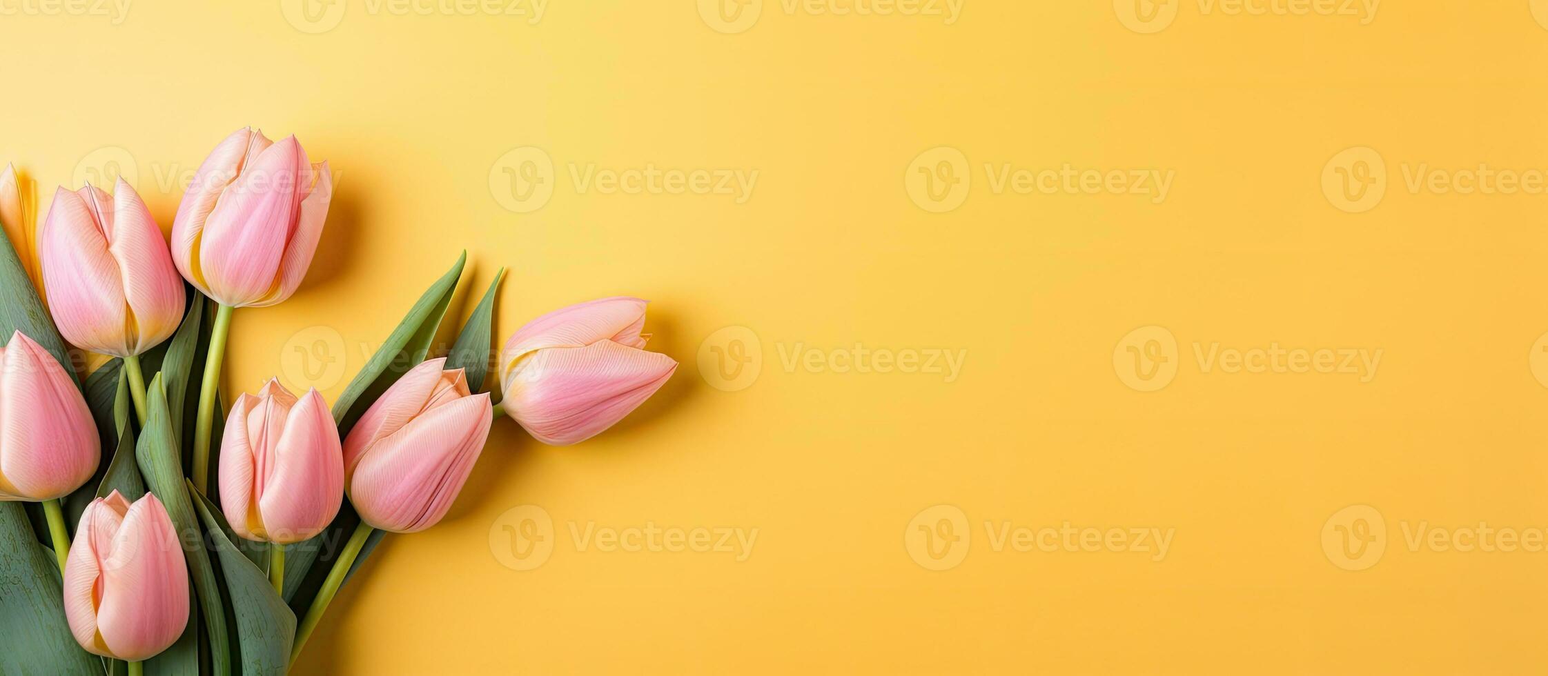 A yellow tulip bouquet is displayed on a cork note board against a pink background. empty space photo