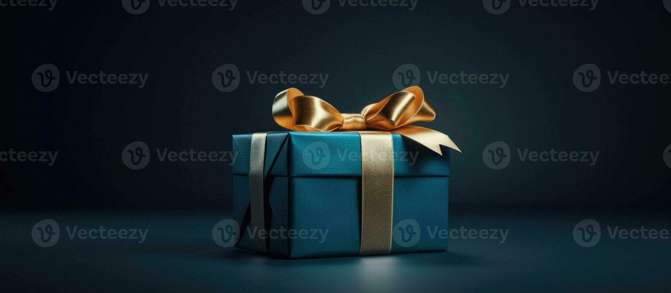 side view monochrome image of a small luxury gift box with a blue bow on a dark blue background. photo