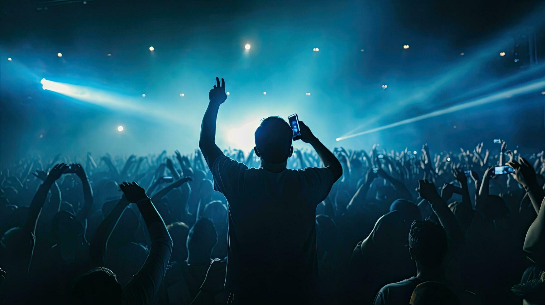 Singer performing on stage in packed stadium with bright lights and fans holding up phones photo