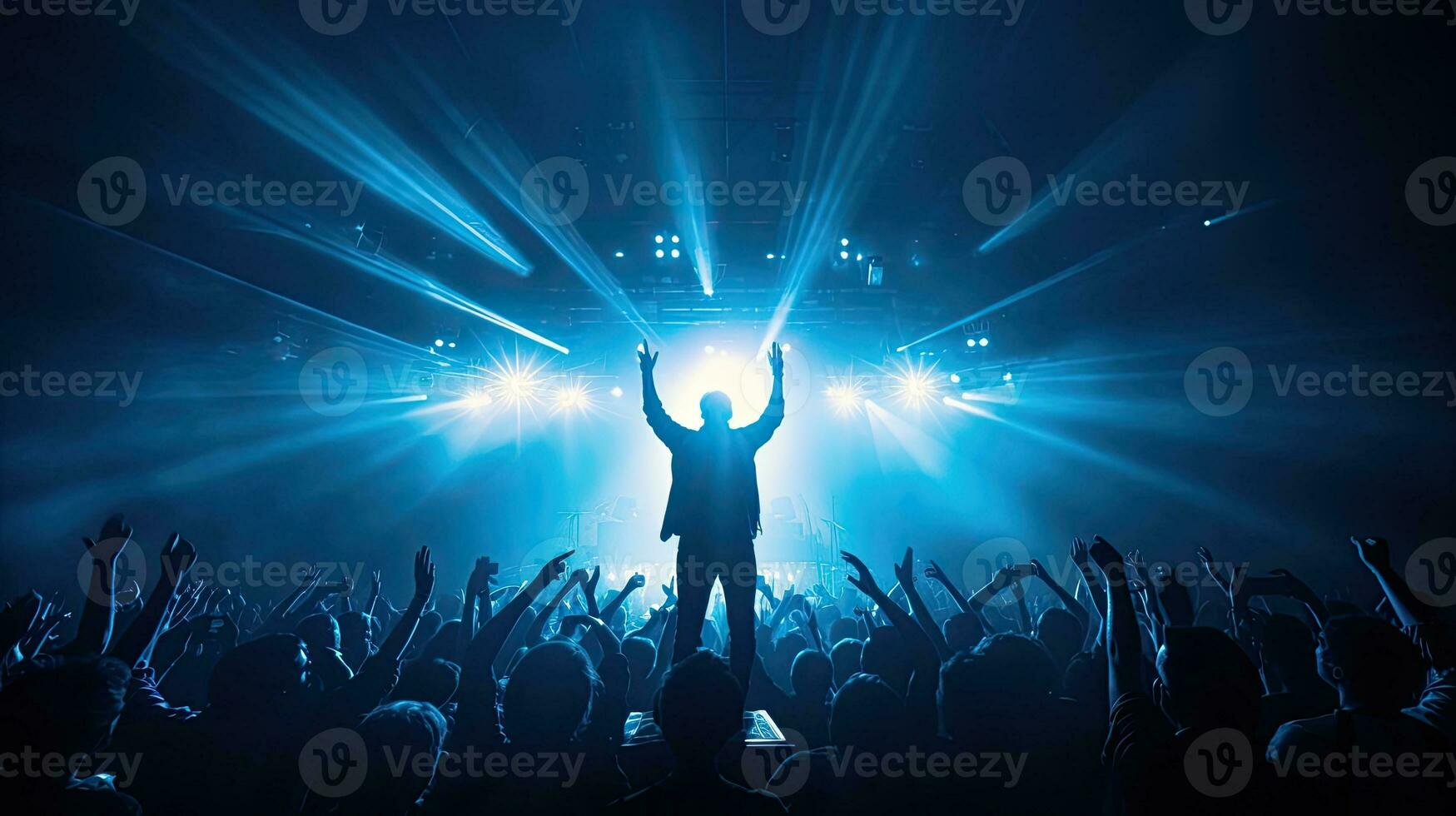 Singer performing on stage in packed stadium with bright lights and fans holding up phones photo
