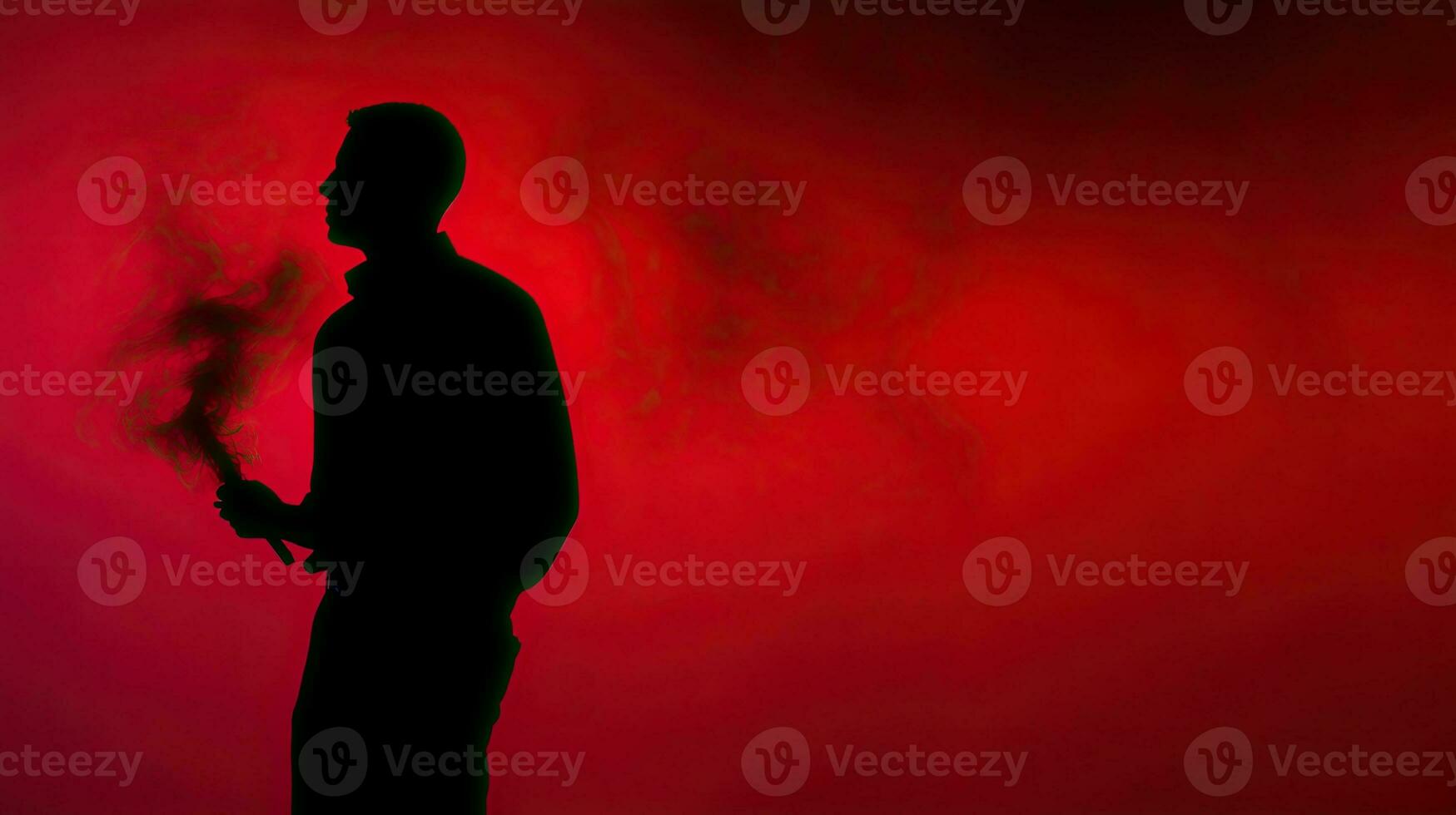 A man with a red smoke stick captured in silhouette photo