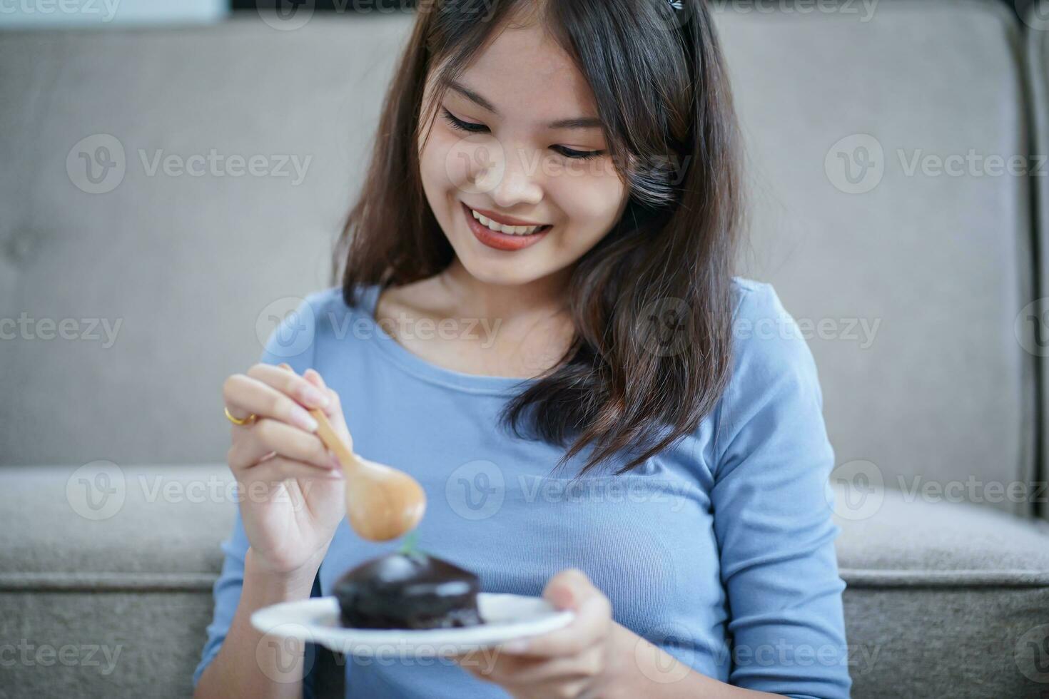 hermosa asiático mujer comiendo sabroso chocolate pastel. adolescente niña comiendo el pastel. foto