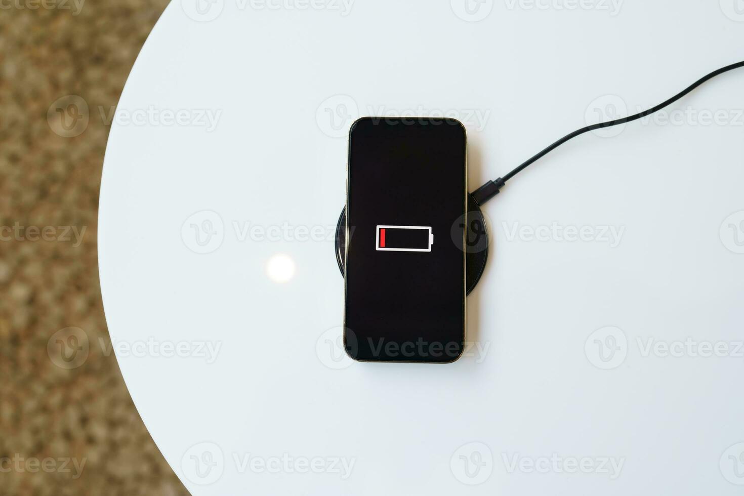Charging mobile phone battery with wireless charging device in the table. Smartphone charging on a charging pad. Mobile phone near wireless charger Modern lifestyle technology concept. photo