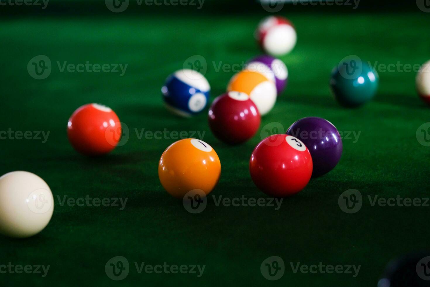 Man's hand and Cue arm playing snooker game or preparing aiming to shoot pool balls on a green billiard table. Colorful snooker balls on green frieze. photo