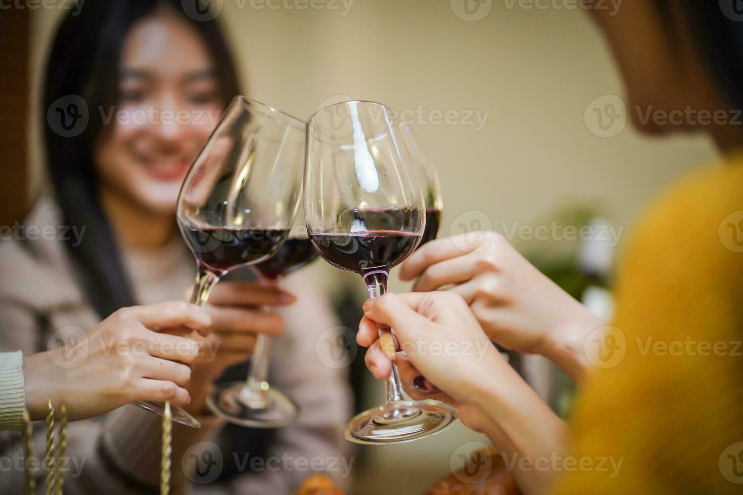 Cheerful friends enjoying home Birthday holiday party. Asian Friends cheering drinking red wine celebrating Christmas or New Year party photo