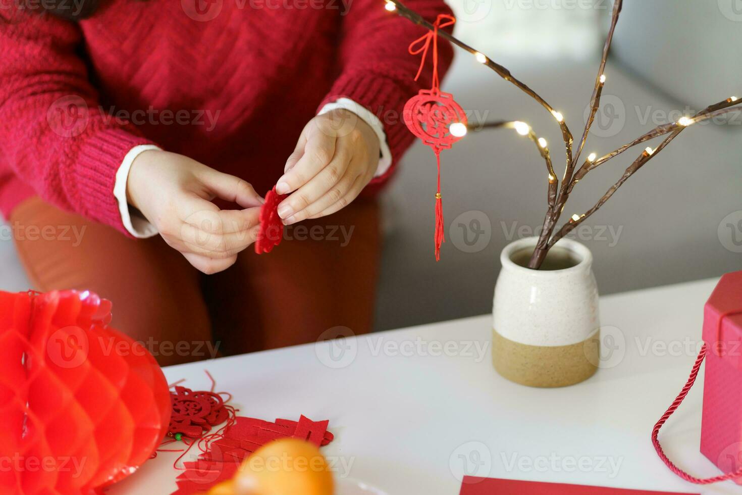 Asian Woman decorated house for Chinese New Year Celebrations. putting traditional pendant to the Chinese Lunar New Year for good luck. Chinese word means blessing photo
