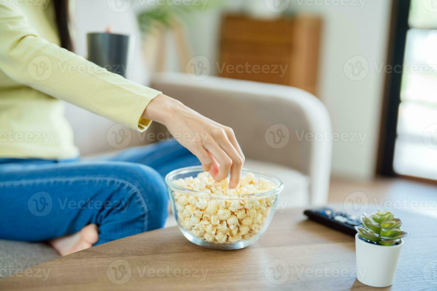 Asian woman Watching smart TV and using remote controller Hand holding television audio remote control at home with the remote control television photo