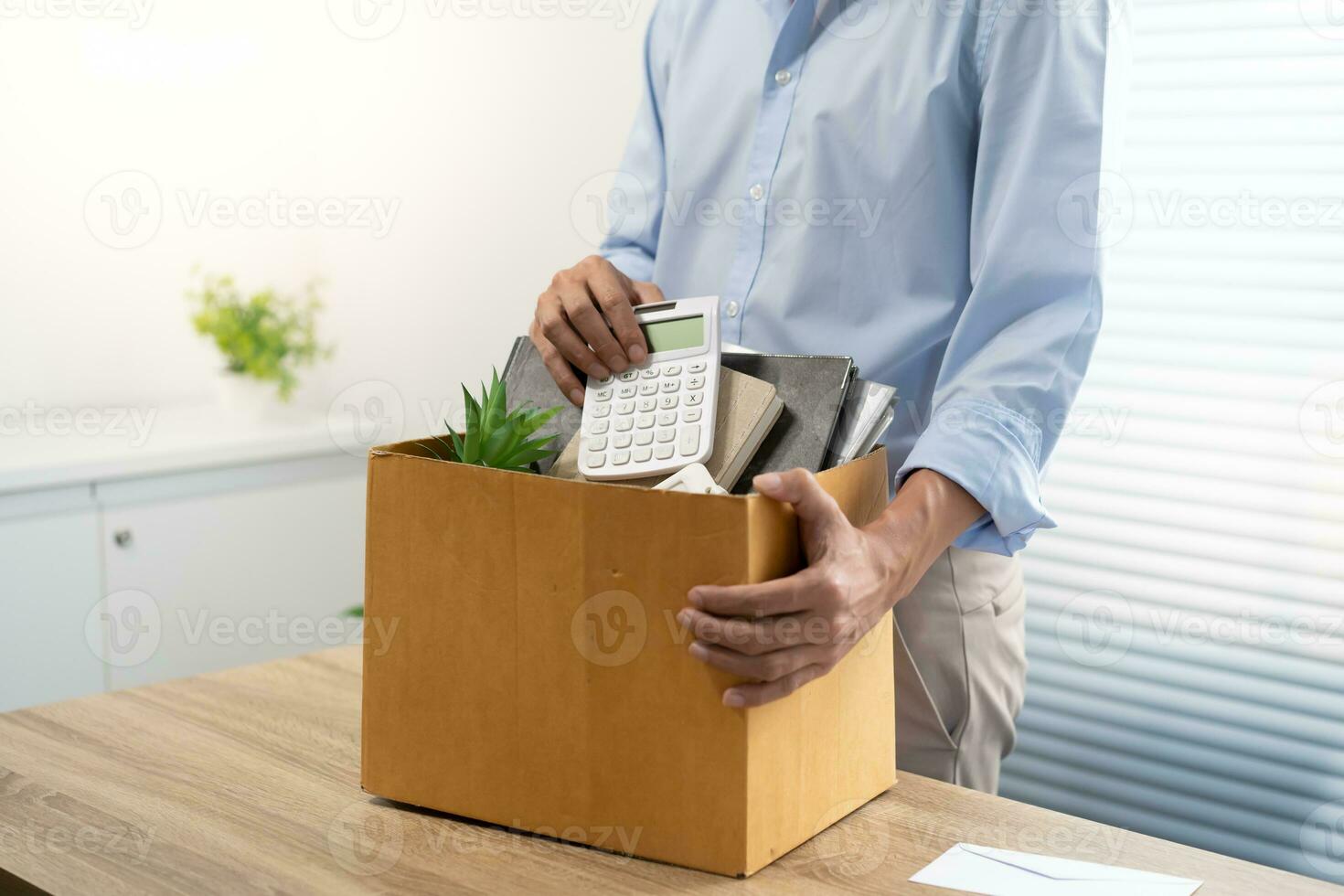 Business man sending resignation letter and packing Stuff Resign Depress or carrying business cardboard box by desk in office. Change of job or fired from company photo