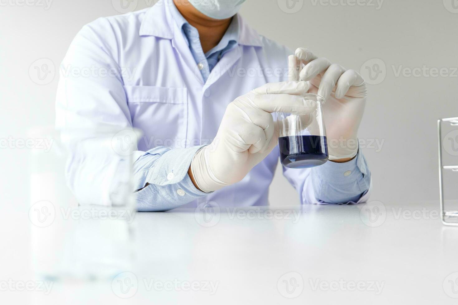 Science innovative Male medical or scientific laboratory researcher performs tests with blue liquid in laboratory. equipment science experiments technology Coronavirus Covid-19 vaccine research photo