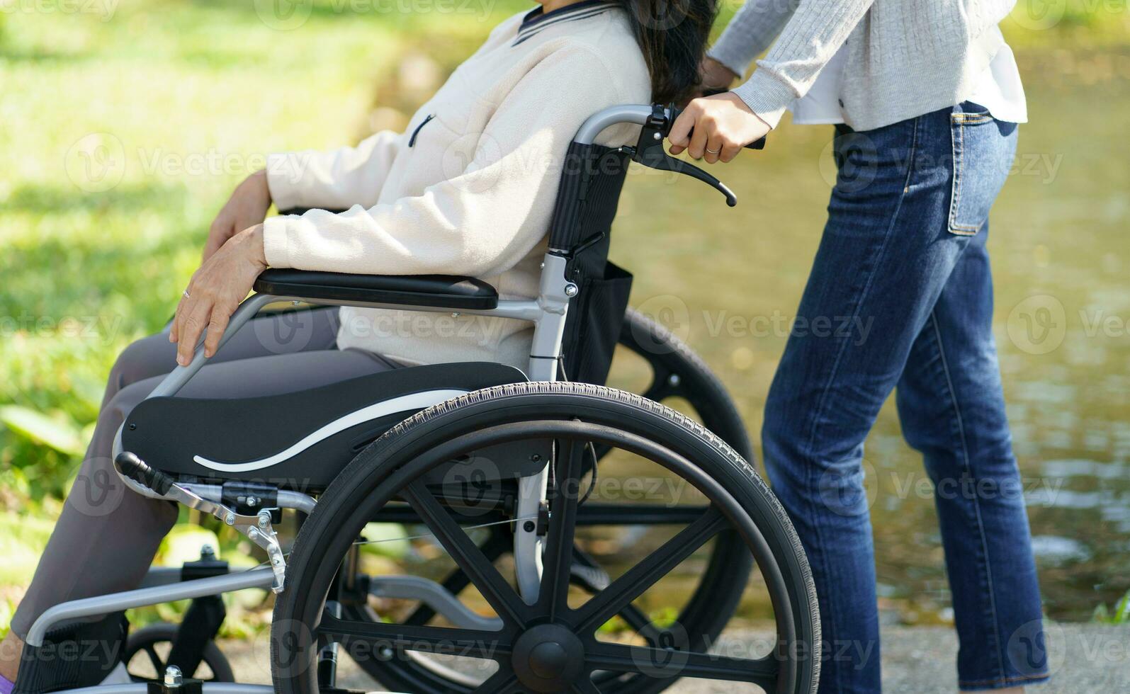 Nursing home. Young caregiver helping senior woman in wheelchair. photo