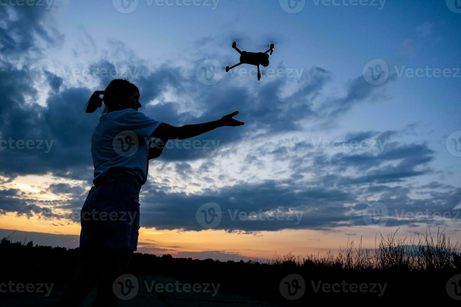 silhouette of woman controlling  drone on sunset background photo