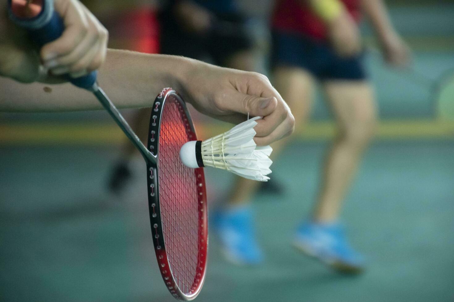 Badminton player holds racket and white cream shuttlecock in front of the net before serving it to another side of the court photo