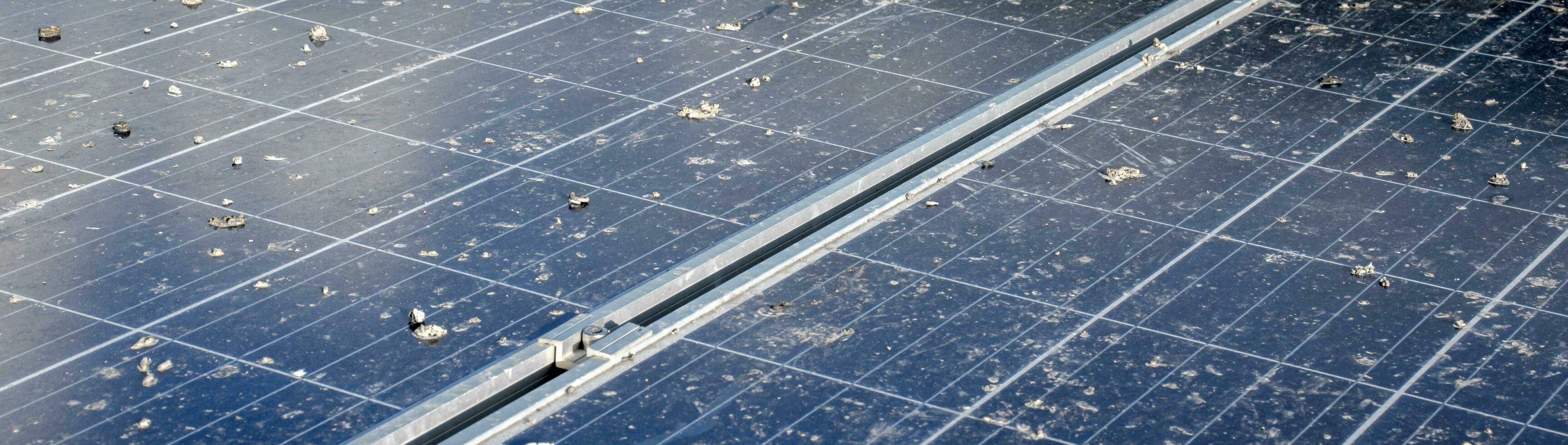 Upper surface of solar rooftop which has been used for a long time is stained with dust, bird droppings, dirt, smog and rainwater stains, concept for cleaning, washing and maintainance, cropped shot. photo
