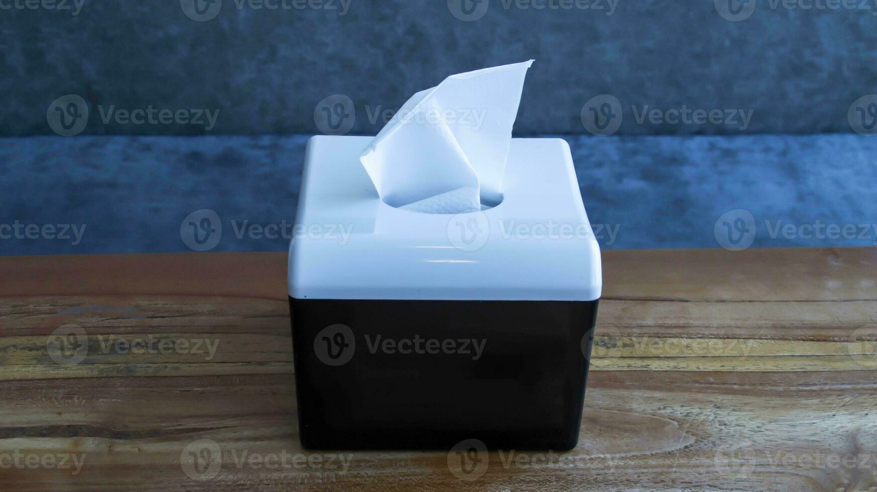 A black tissue box at the wooden table. photo